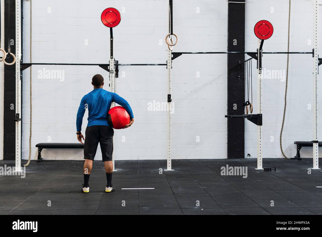 Athlète avec Medicine ball regardant l'équipement d'exercice dans la salle de gym Banque D'Images