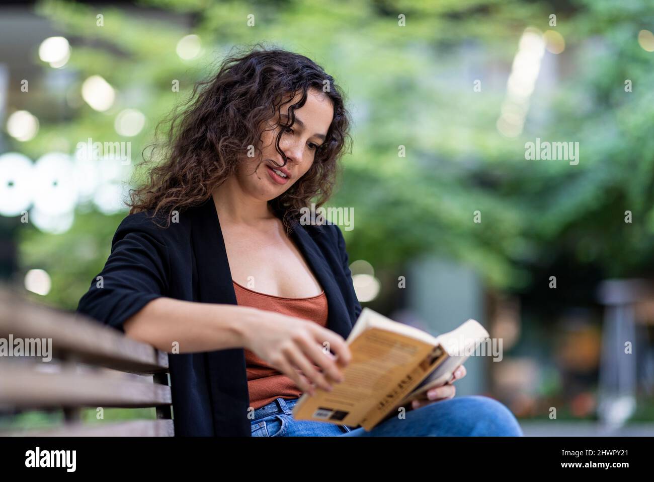 Jeune femme lisant le livre sur le banc dans le parc Banque D'Images