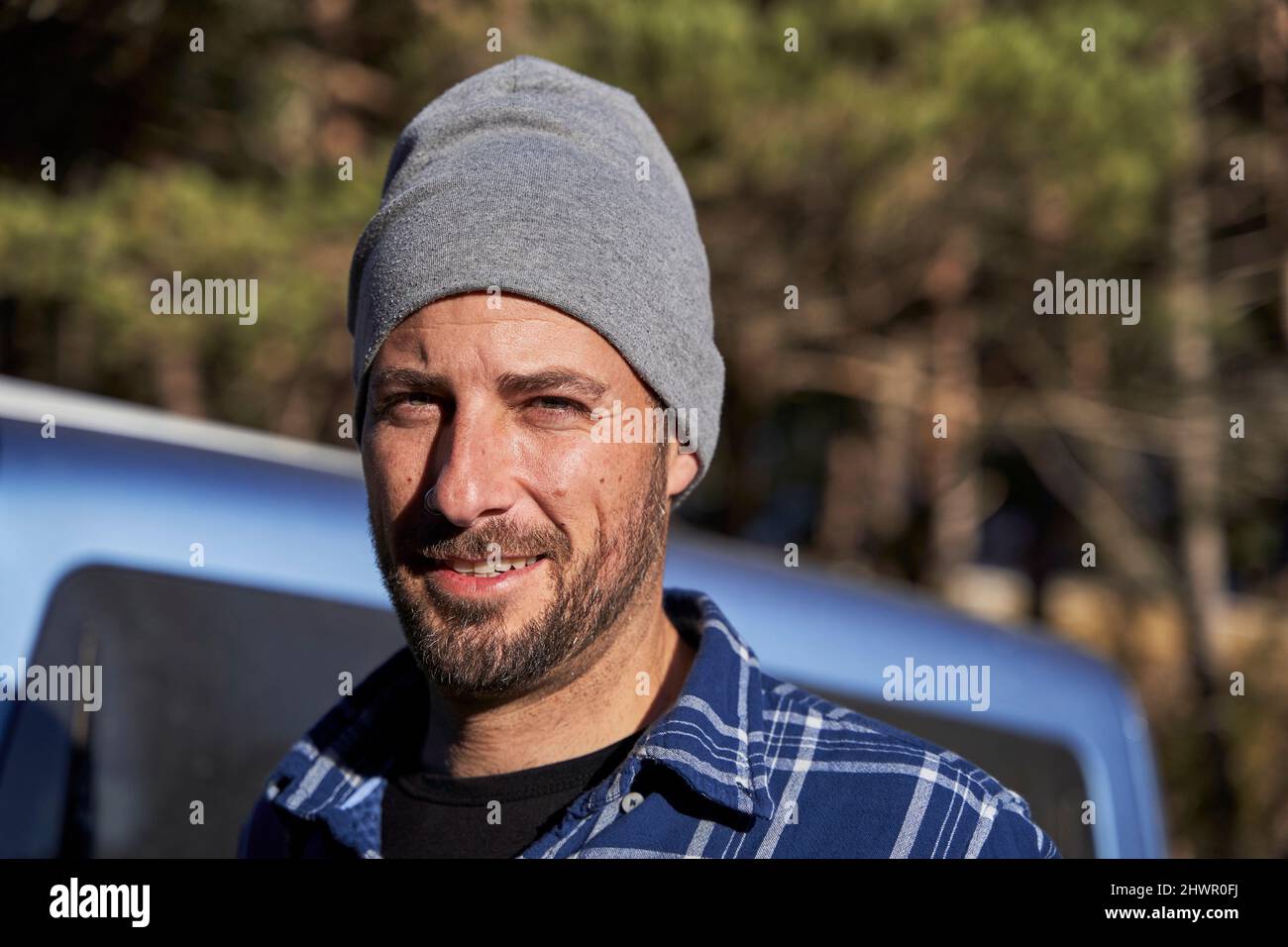 Homme portant un chapeau tricoté debout en voiture le jour ensoleillé Banque D'Images