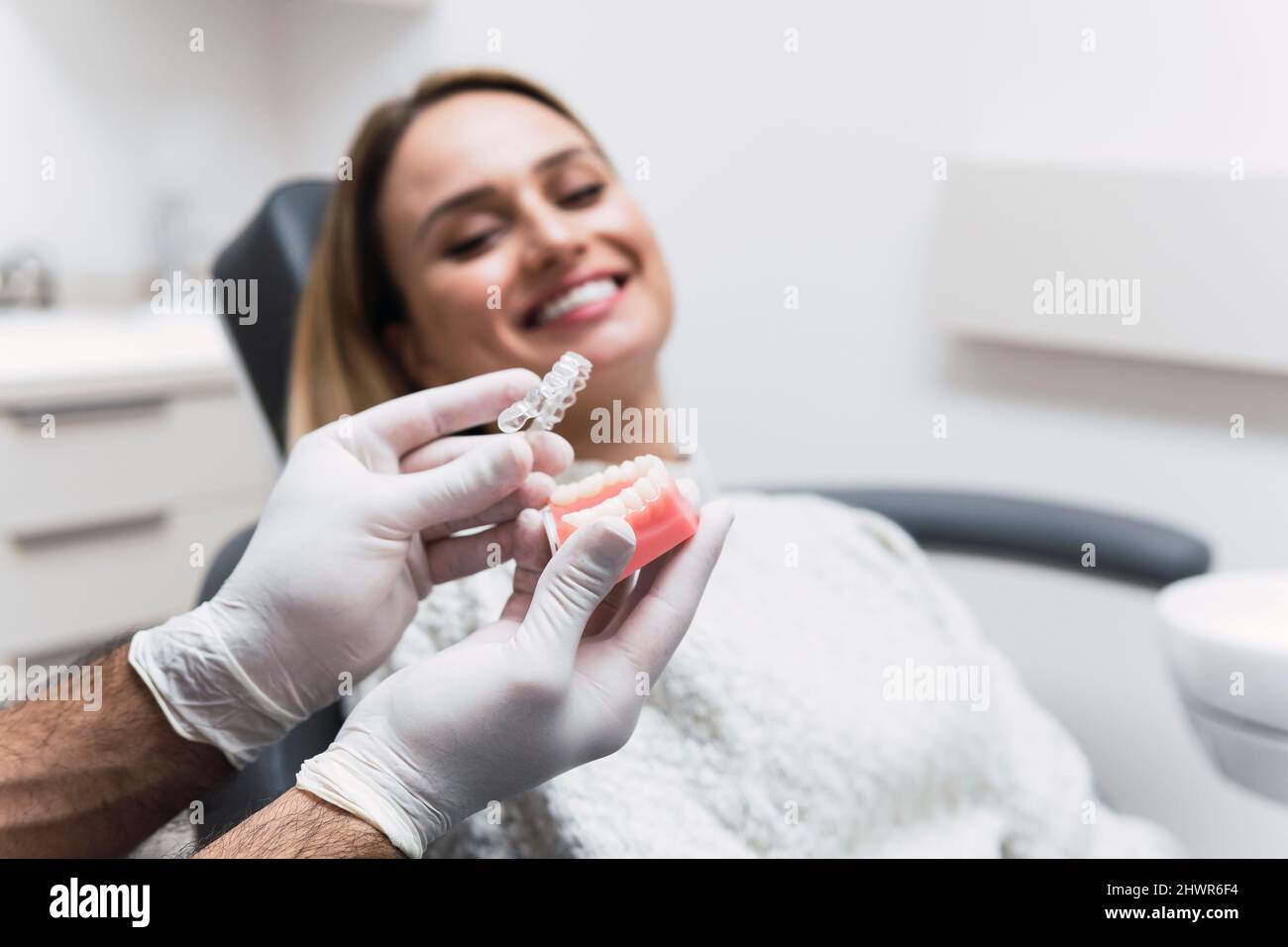 Dentiste tenant des prothèses dentaires par le patient au cabinet médical Banque D'Images