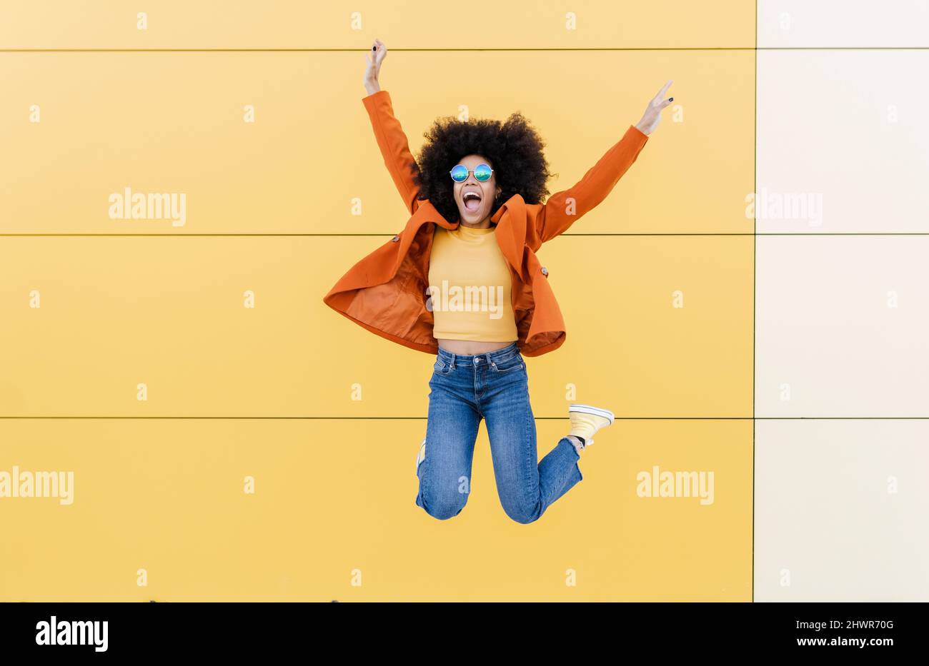 Bonne femme sautant devant le mur Banque D'Images