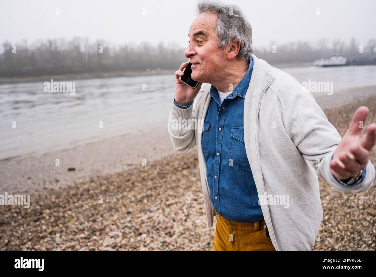 Homme senior parlant sur un smartphone à la plage Banque D'Images