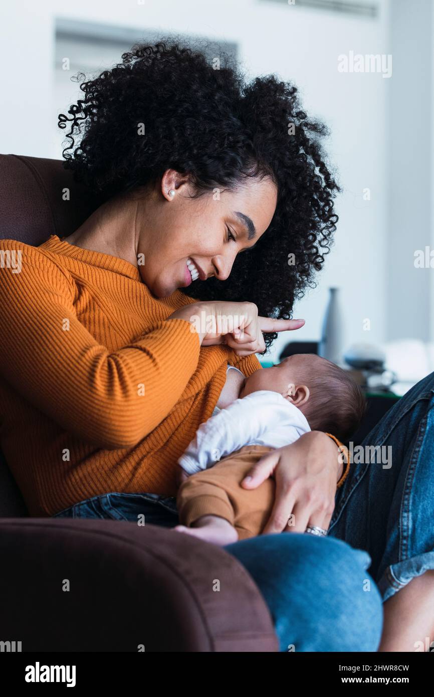 Mère allaitant bébé garçon dans le salon à la maison Banque D'Images