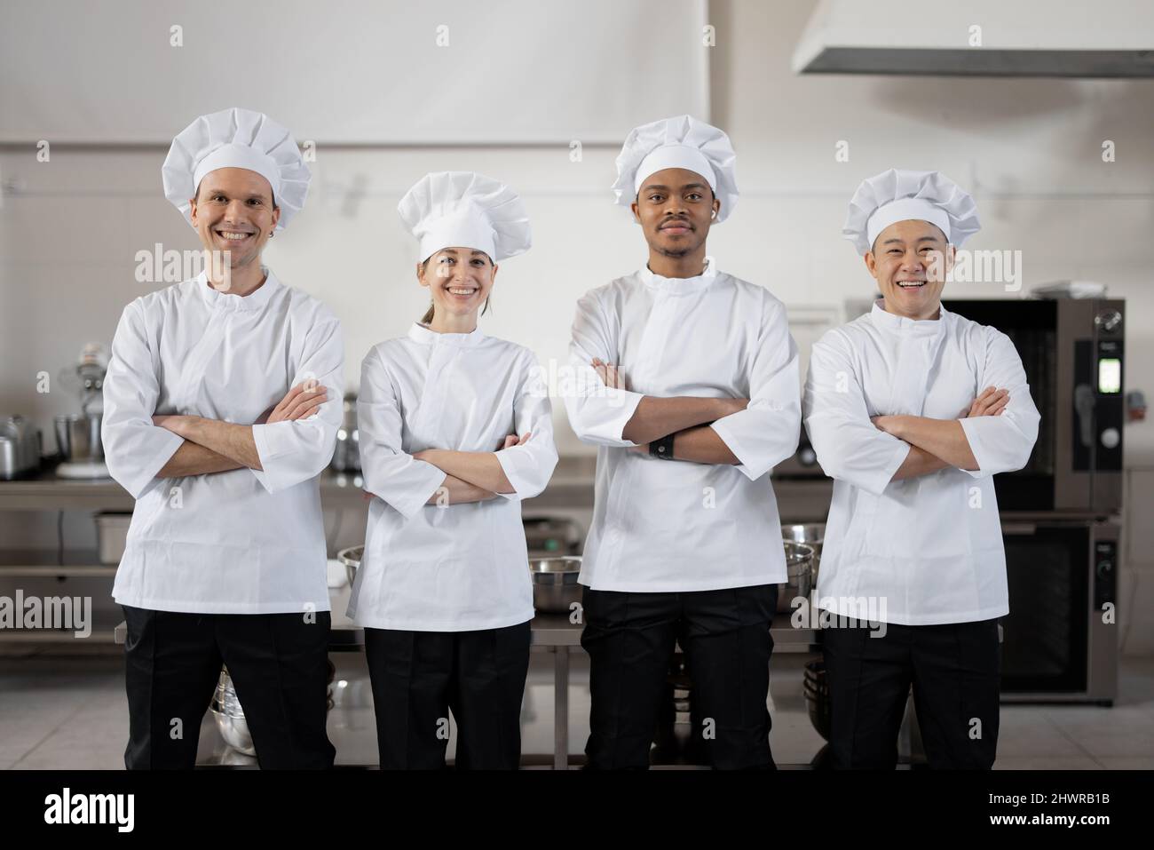 Portrait d'un jeune groupe multiracial de cuisiniers debout ensemble en uniforme dans la cuisine du restaurant. Des chefs confiants prêts à cuisiner au restaurant. Équipe de professionnels européens, asiatiques et latins Banque D'Images