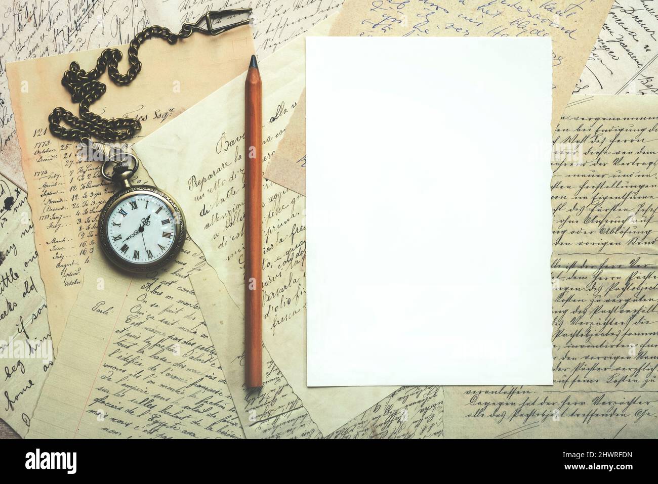 Feuille blanche avec espace de copie et cartes postales à côté d'une vieille horloge et d'un crayon Banque D'Images