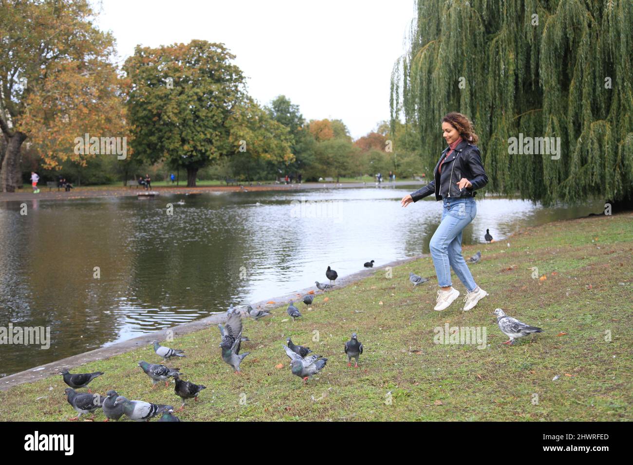 Fille qui court avec des pigeons dans le Regent Park de Londres Banque D'Images