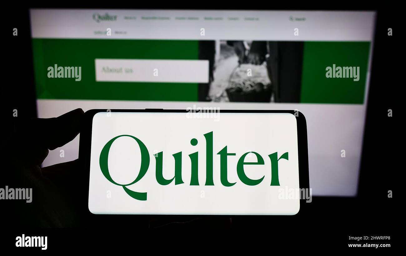 Personne tenant un smartphone avec le logo de la société britannique de gestion de patrimoine Quilter plc à l'écran devant le site Web. Mise au point sur l'affichage du téléphone. Banque D'Images