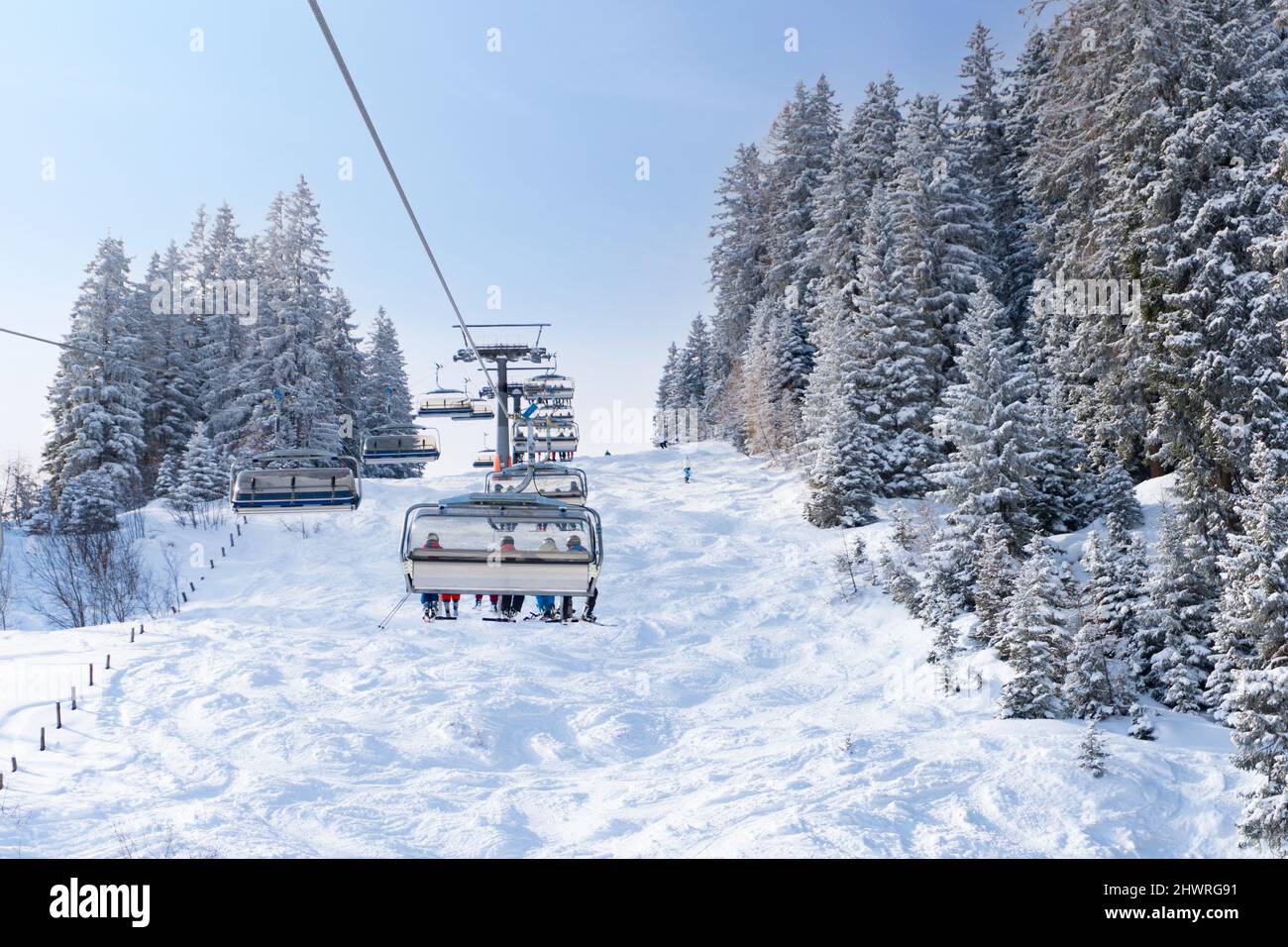 Télésiège moderne dans la station de ski pendant les vacances d'hiver. Des arbres enneigés et une piste de ski naturelle. Banque D'Images