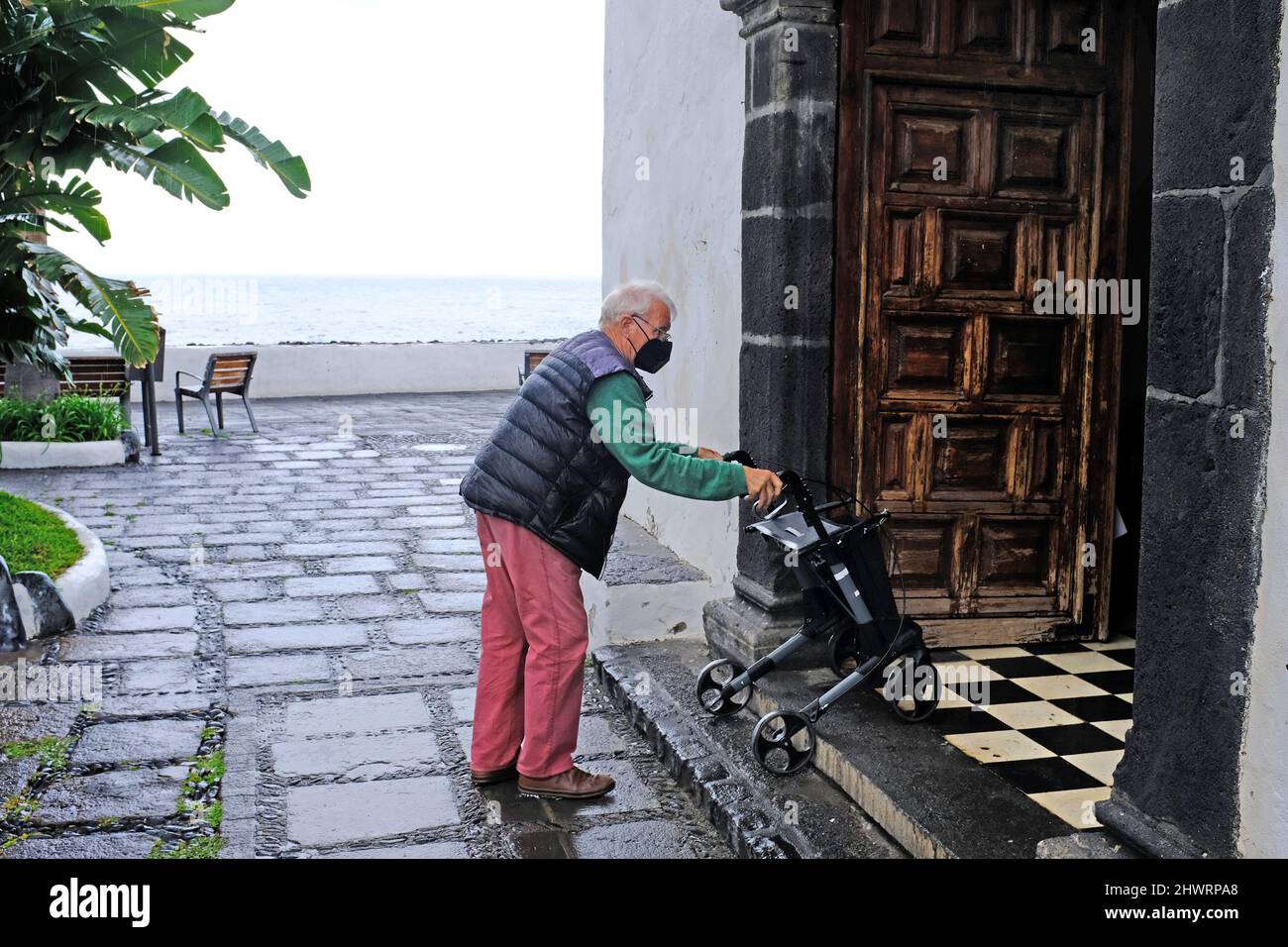 Un homme âgé avec un cadre de marche entrant dans une église à puerto de la cruz, Tenerife Banque D'Images