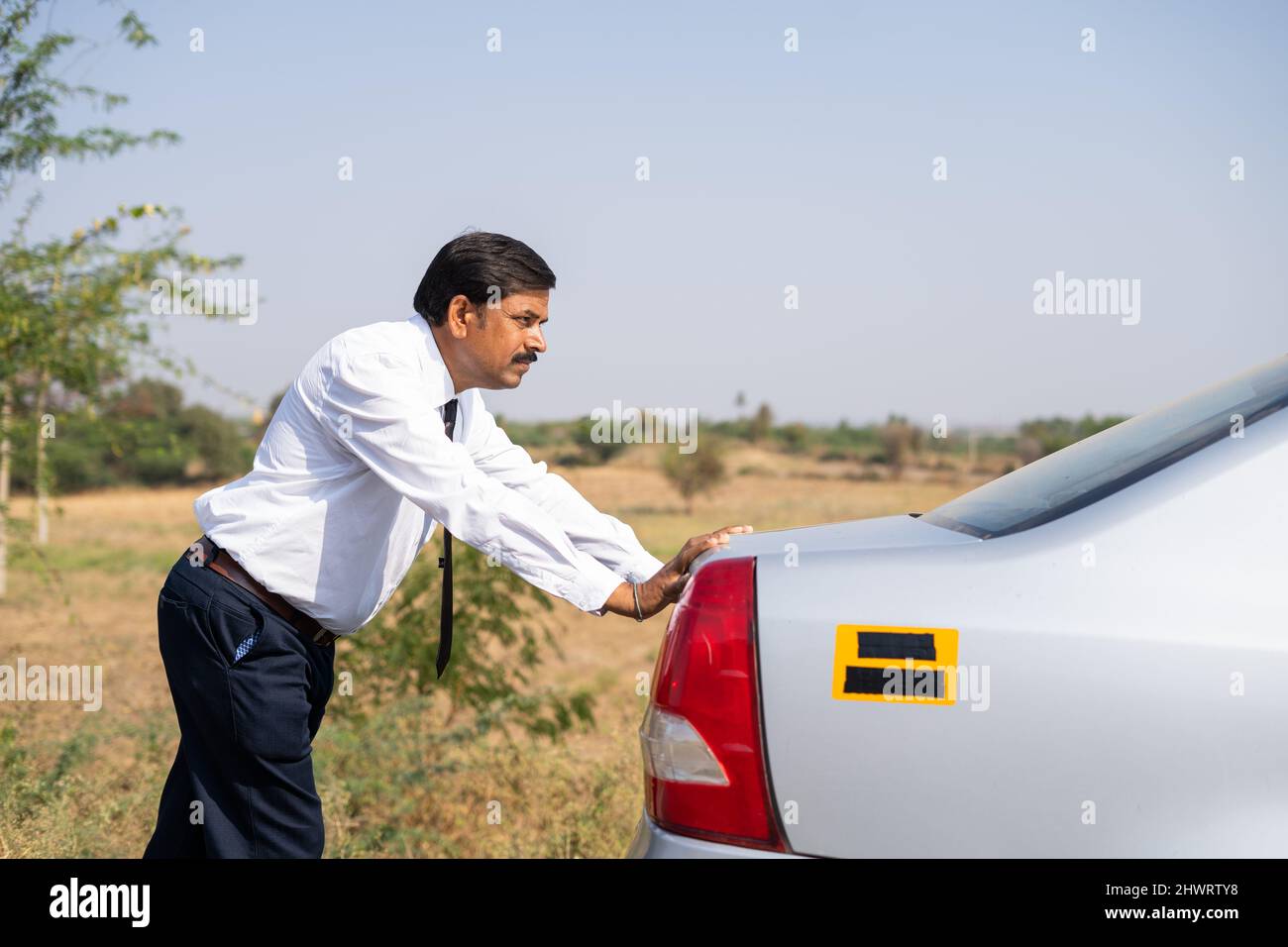 Homme d'affaires en faisant du tort à une voiture cassée par temps chaud et ensoleillé - concept de crise de l'essence, malheur et frustration Banque D'Images