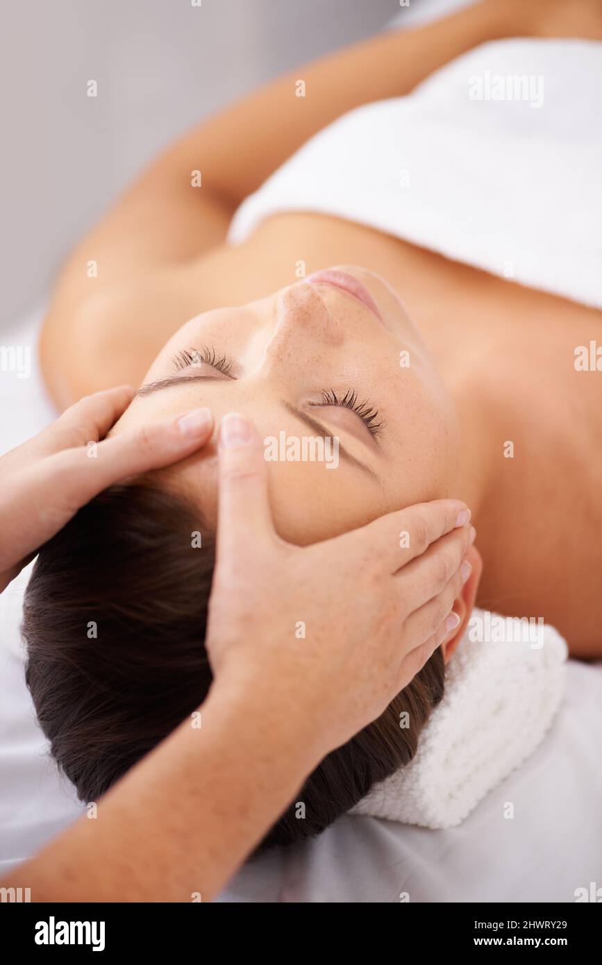 Se détendre dans un lieu calme. Une jeune femme couché dans un centre de beauté recevant un massage relaxant de la tête. Banque D'Images