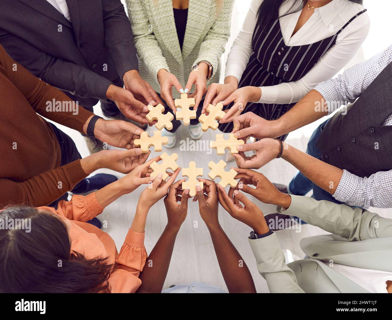 Groupe d'hommes et de femmes d'affaires multiraciaux reliant des pièces d'un puzzle Banque D'Images
