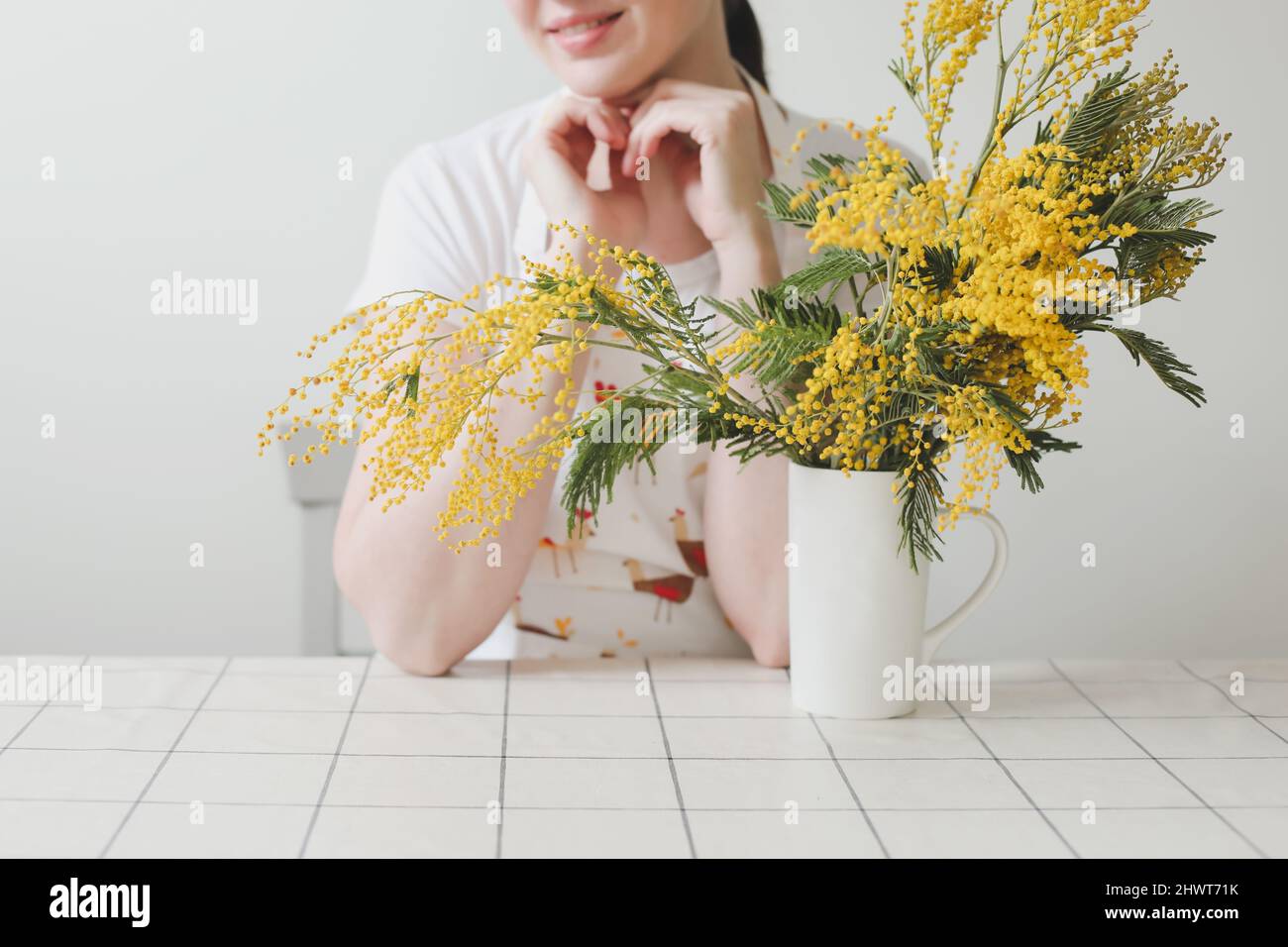 Belle jeune femme souriante avec fleurs mimosa sur fond blanc. Banque D'Images