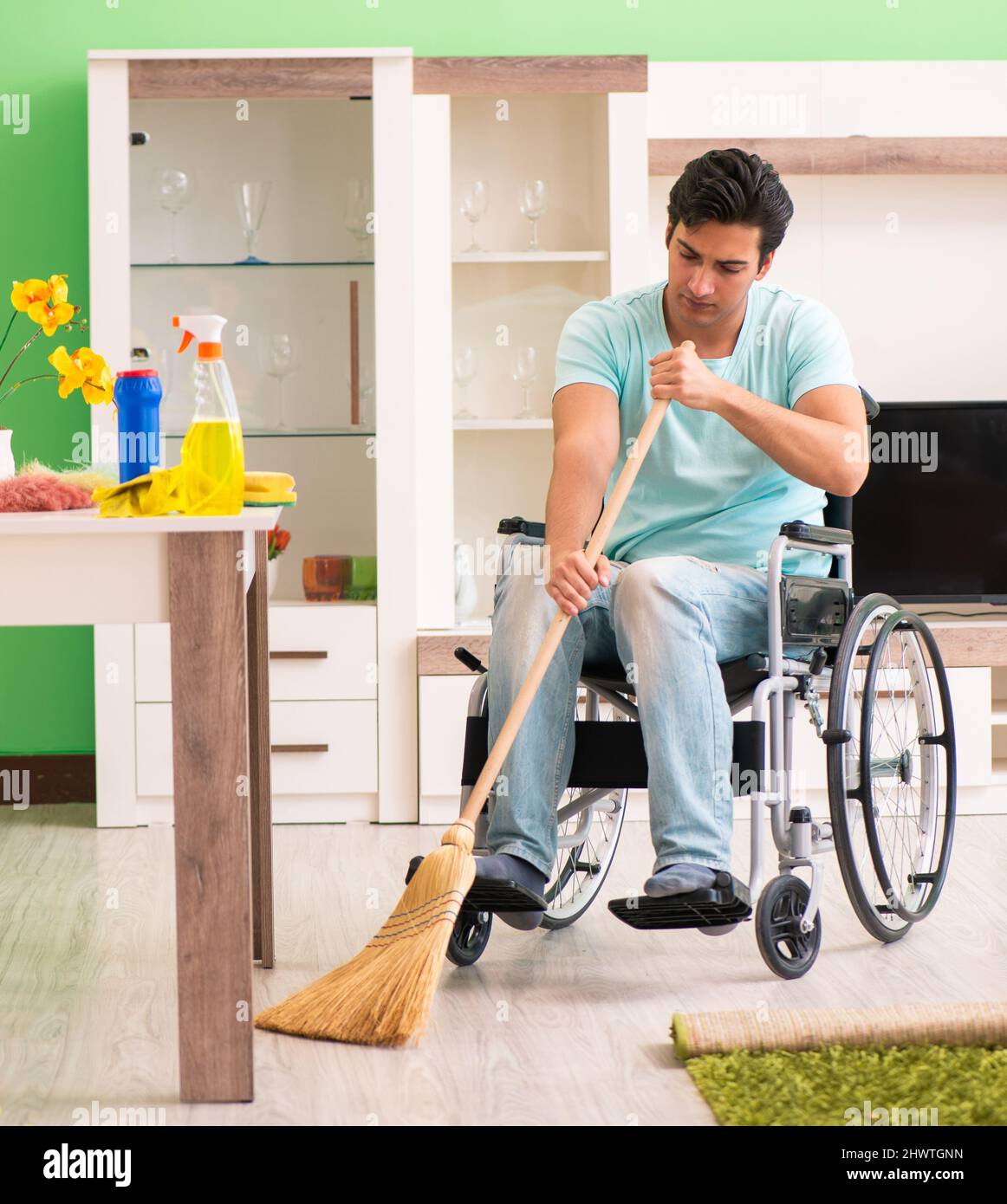 L'homme handicapé sur fauteuil roulant chambre de nettoyage Photo Stock -  Alamy
