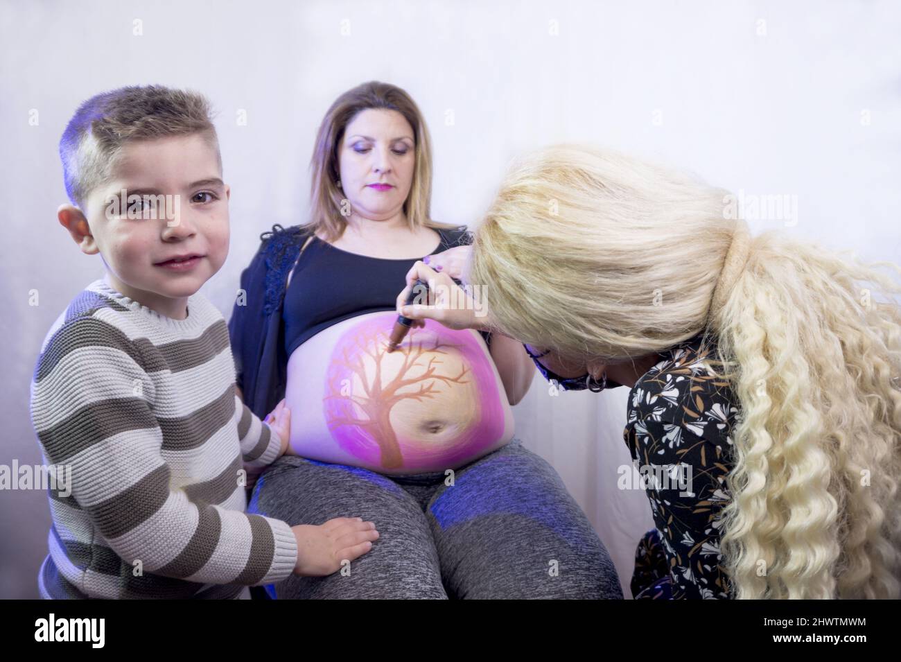 Femme enceinte de huit mois avec un fils de trois ans. Peinture du corps Banque D'Images