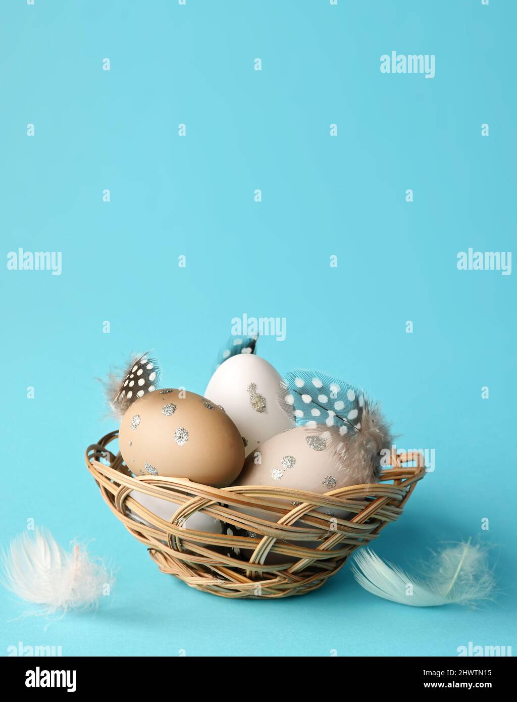 Oeufs de Pâques dans un nid avec des plumes sur fond bleu. Concept de vacances. Banque D'Images