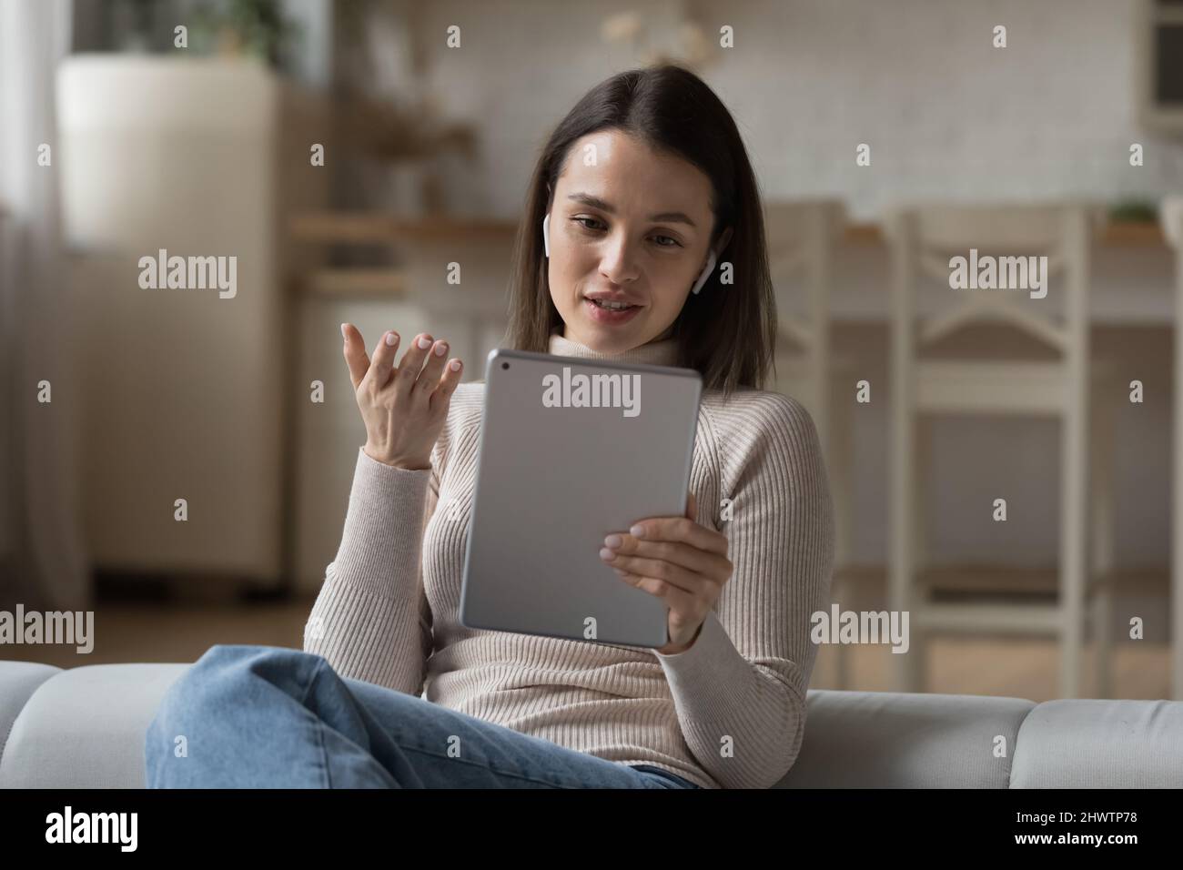 Femme porter des écouteurs sans fil prendre part à l'utilisation de videocall tablette Banque D'Images