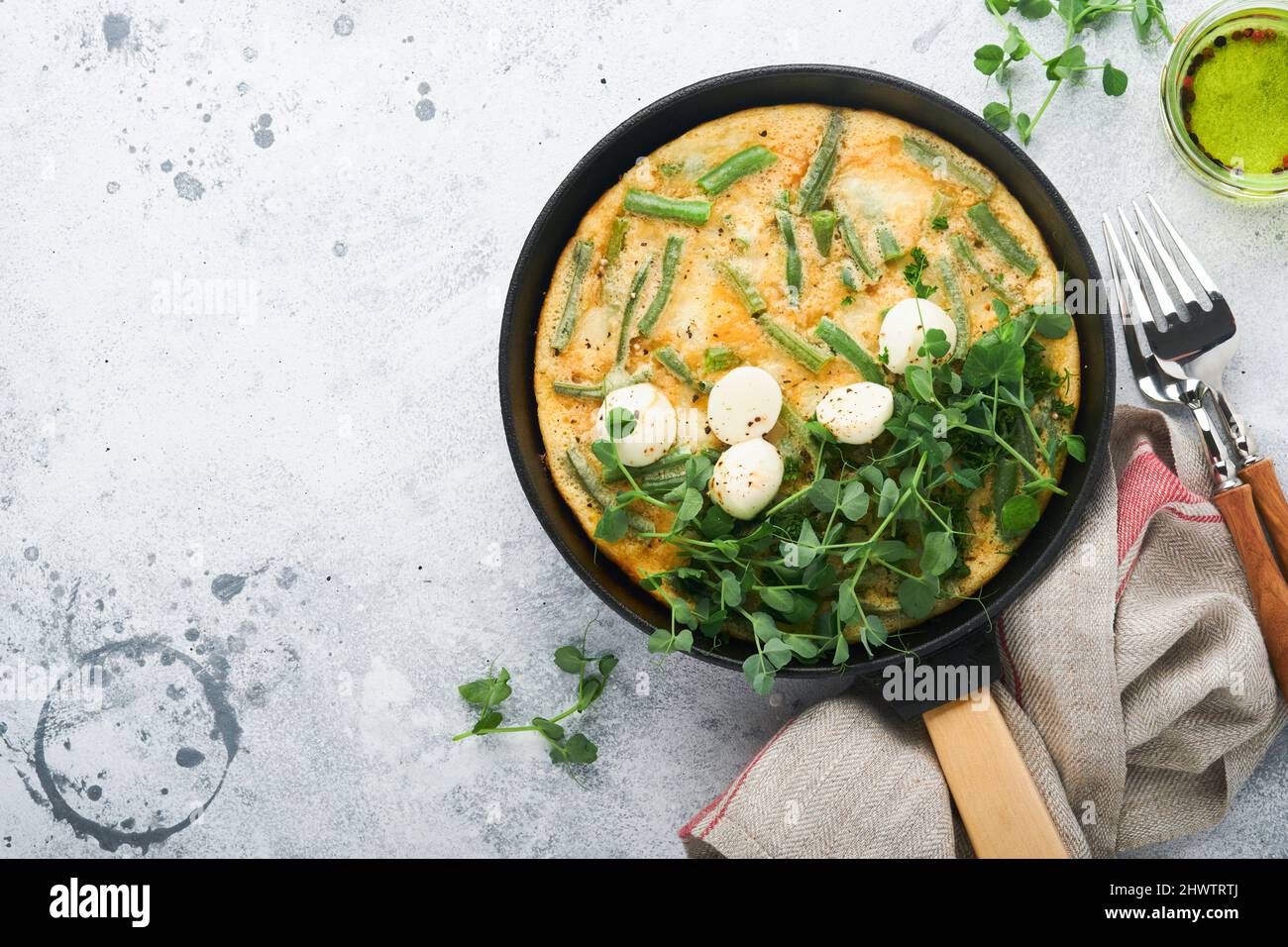 Omelette aux épinards, haricots verts, pommes de terre et épinards aliments sains dans une poêle noire sur fond rustique vieux de pierre grise. Frittata traditionnelle pour br Banque D'Images