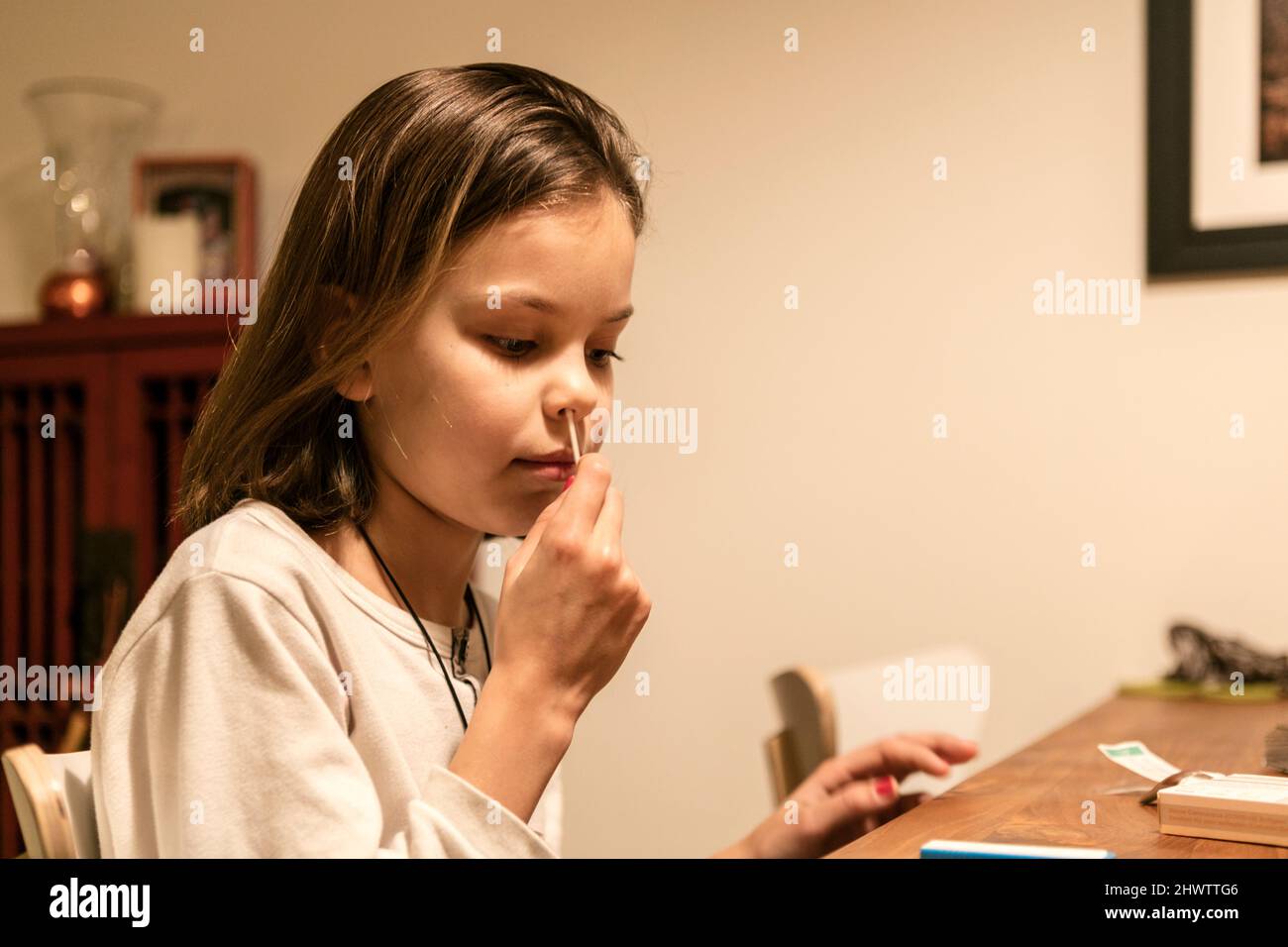 Une jeune fille a écouvillonnage sa narine tout en prenant un test rapide d'antigène covid19 à la table de petit déjeuner avant l'école, à Amsterdam, aux pays-Bas. Banque D'Images