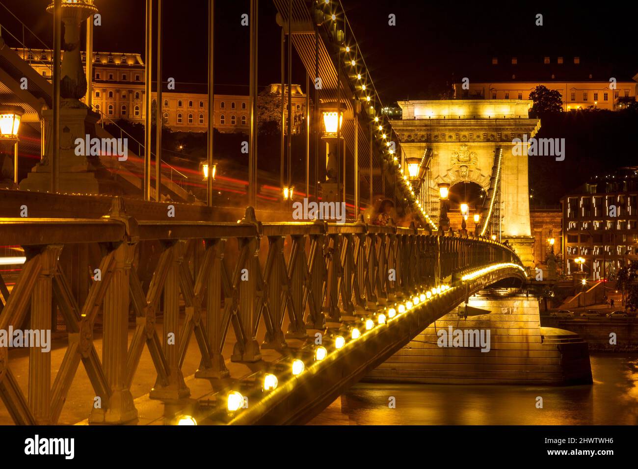 Le célèbre pont de la chaîne Széchenyi à Budapest, en Hongrie, illuminé au-dessus du Danube. Exposition longue avec des pistes lumineuses de voitures la nuit. Banque D'Images