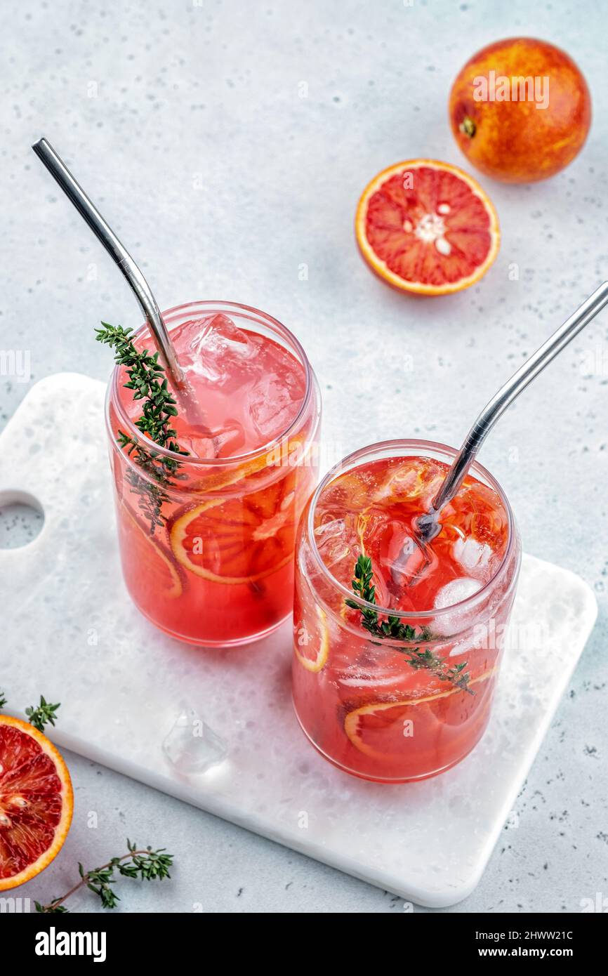 Cocktail de limonade d'orange de sang avec glace et thym sur fond de béton gris clair Banque D'Images