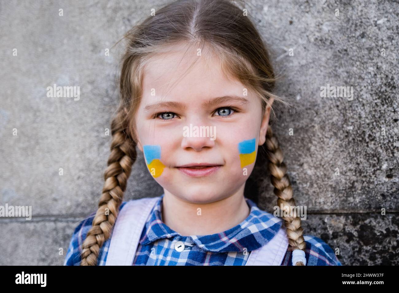 Portrait d'une fille effroyée avec drapeau peint sur la joue dans les couleurs jaune-bleu du drapeau ukrainien. Concept de paix et de protection des enfants Banque D'Images