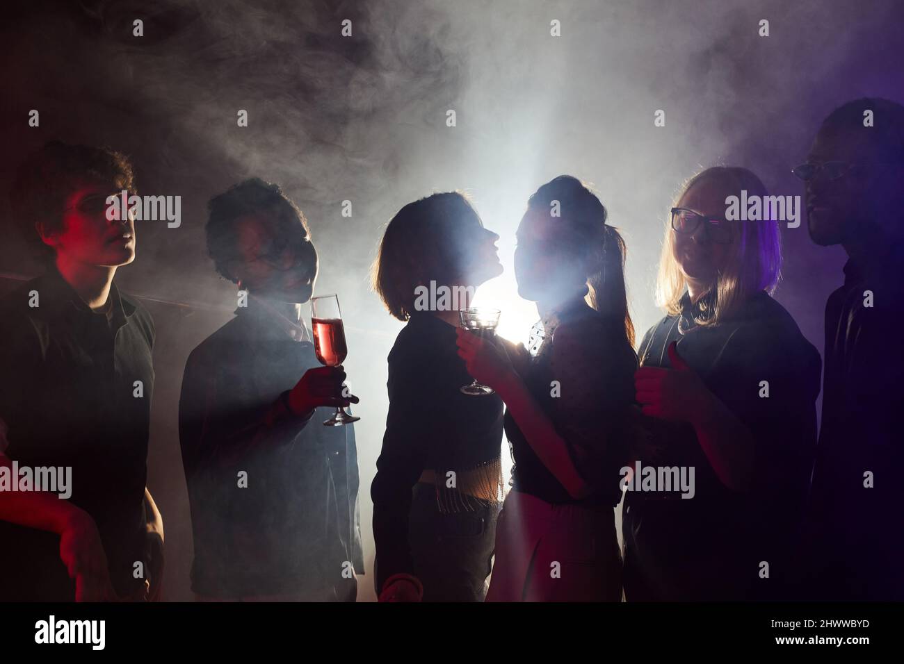 Photo rétro-éclairée de jeunes dansant à la fête, silhouettes en club fumé Banque D'Images