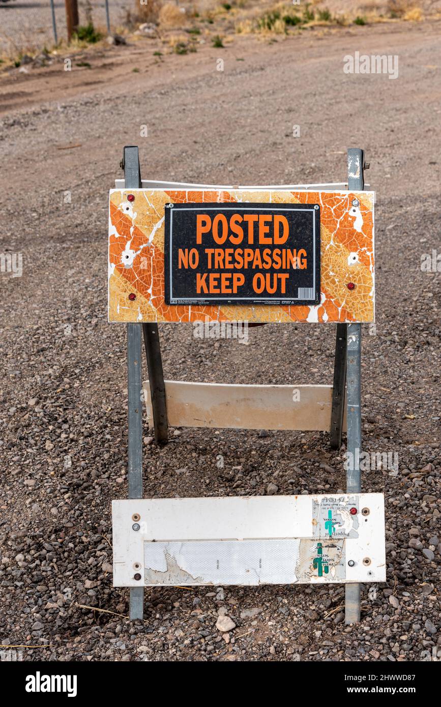 Une barricade pliante rayée, décolorée et sale avec des pieds en métal, des feuilles réfléchissantes qui s'écaillent et un panneau qui lit, affiché pas d'intrusion Défense d'entrer. Banque D'Images