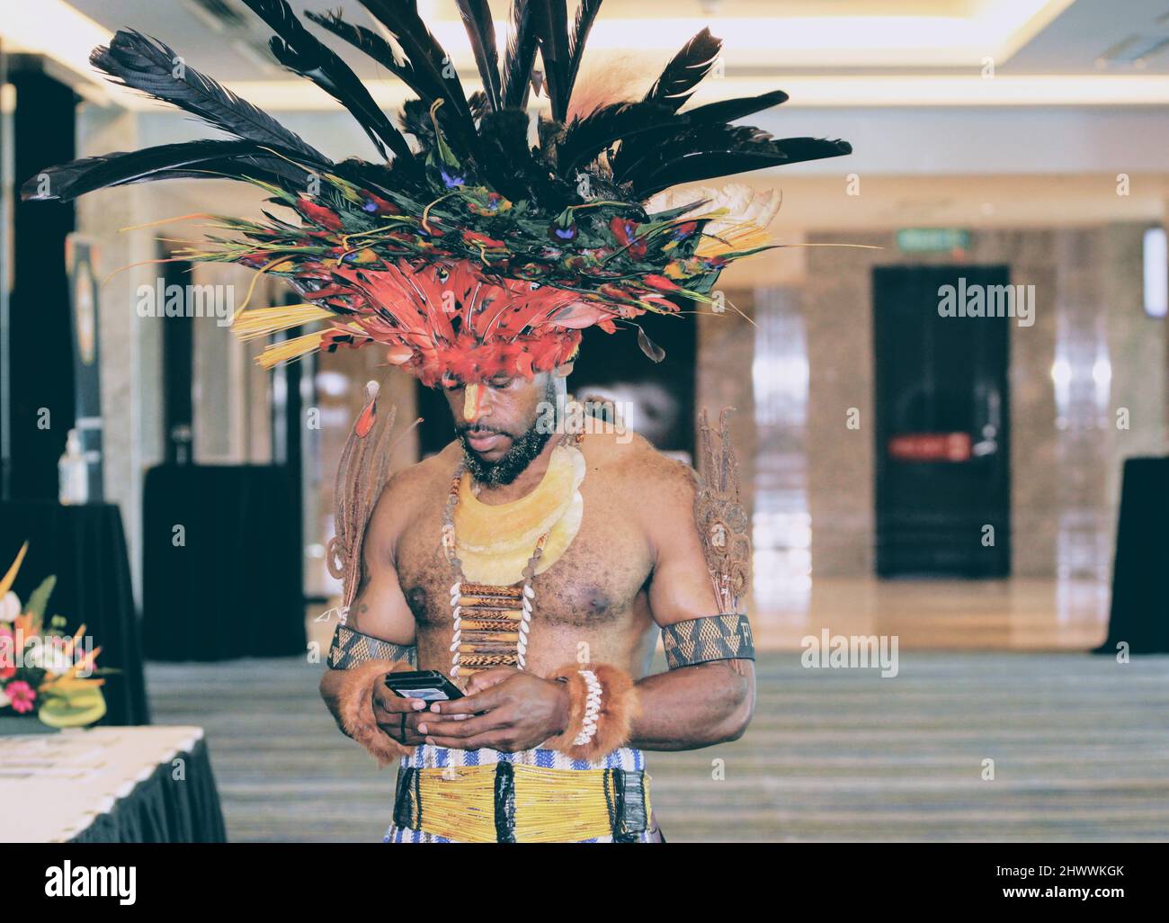 Un highlander de Papouasie-Nouvelle-Guinée dans une tenue traditionnelle utilisant un smartphone à la salle de bal Kokoda du Stanley Hotel & Suites. Banque D'Images