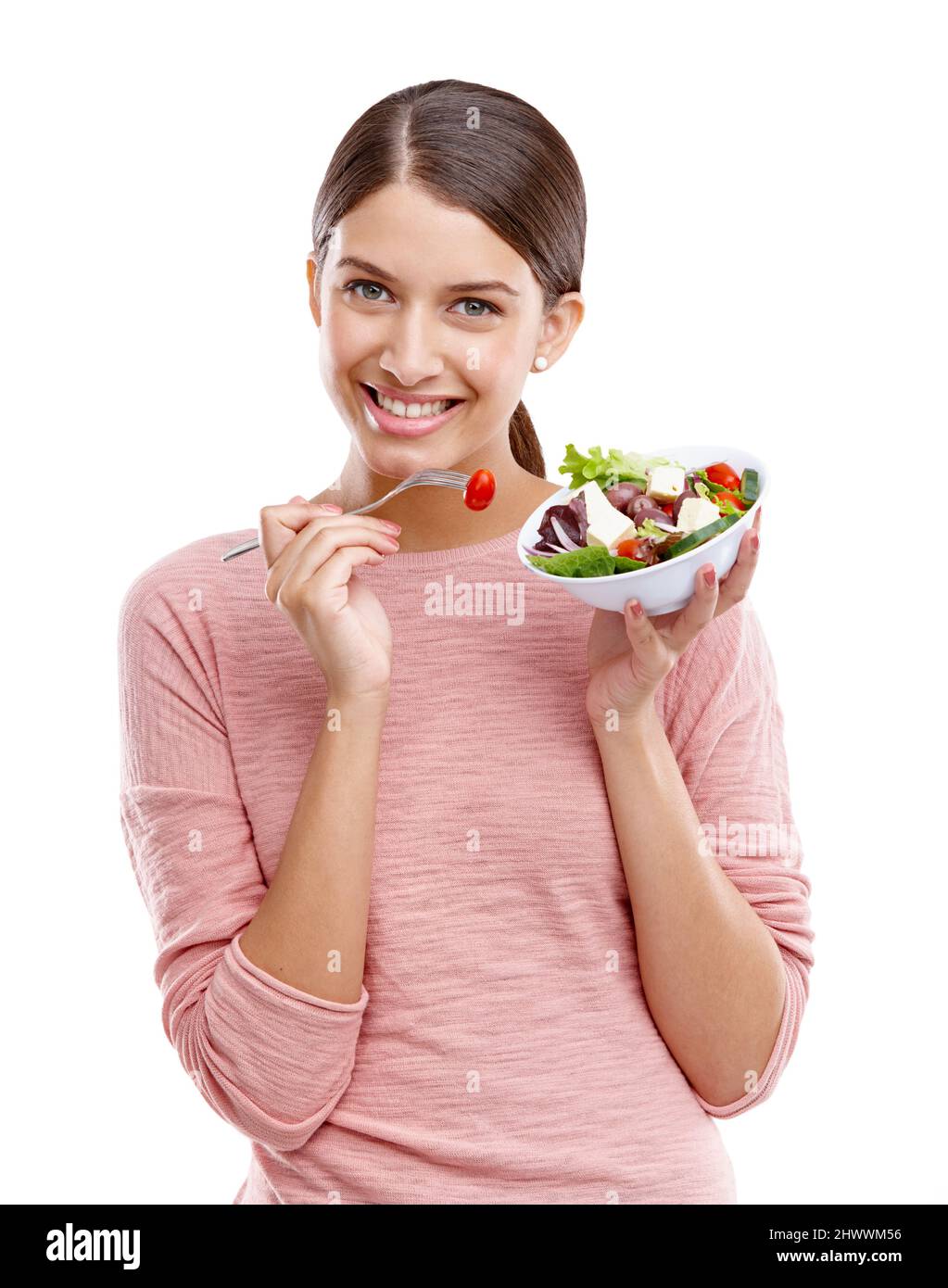 Frais et délicieux. Studio portrait d'une belle jeune femme mangeant une salade saine. Banque D'Images