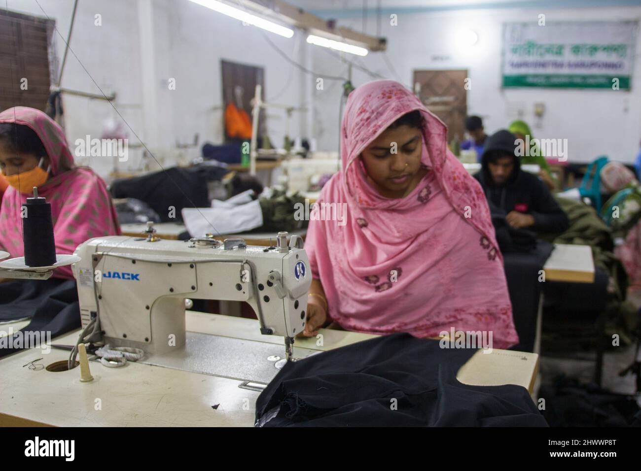 Les travailleurs du vêtement au travail sur la ligne de production dans une usine de vêtements au Bangladesh. Banque D'Images