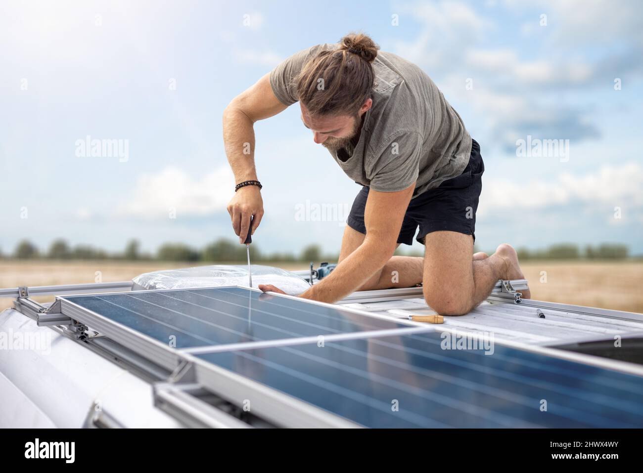 Personne travaillant sur des panneaux solaires au-dessus d'une fourgonnette Banque D'Images