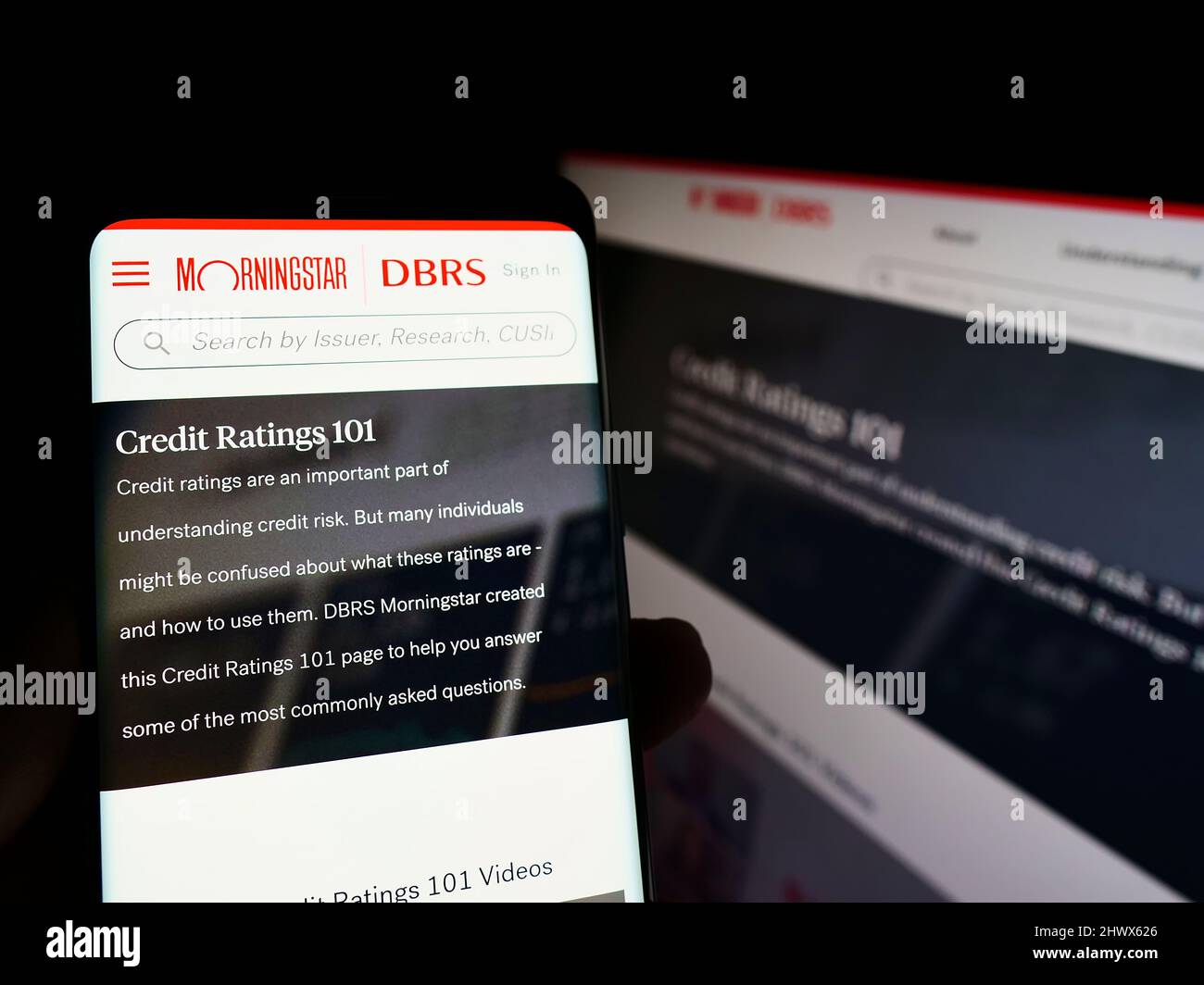 Personne tenant un smartphone avec le site Web de la société canadienne de notation de crédit DBRS Morningstar à l'écran avec moniteur. Concentrez-vous sur le centre de l'écran du téléphone. Banque D'Images