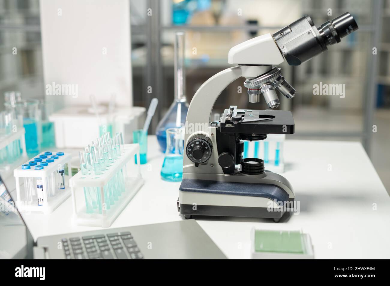 Lieu de travail d'un chercheur ou d'un scientifique contemporain dans un laboratoire de clinique équipé d'un microscope, de flacons et d'un ordinateur portable Banque D'Images