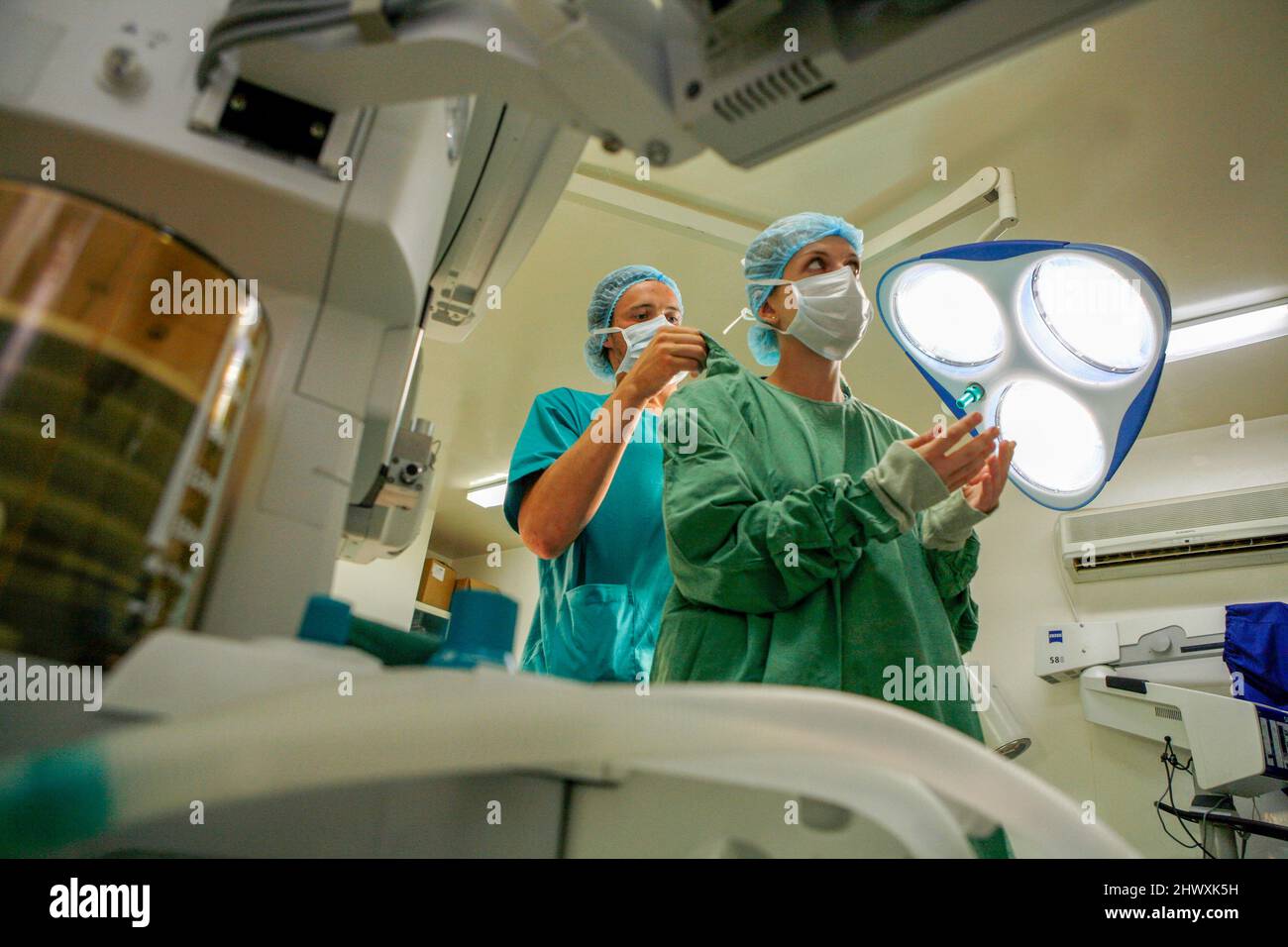 Un assistant aide le chirurgien avec ses vêtements de protection (MODÈLE RELÂCHÉ). Banque D'Images
