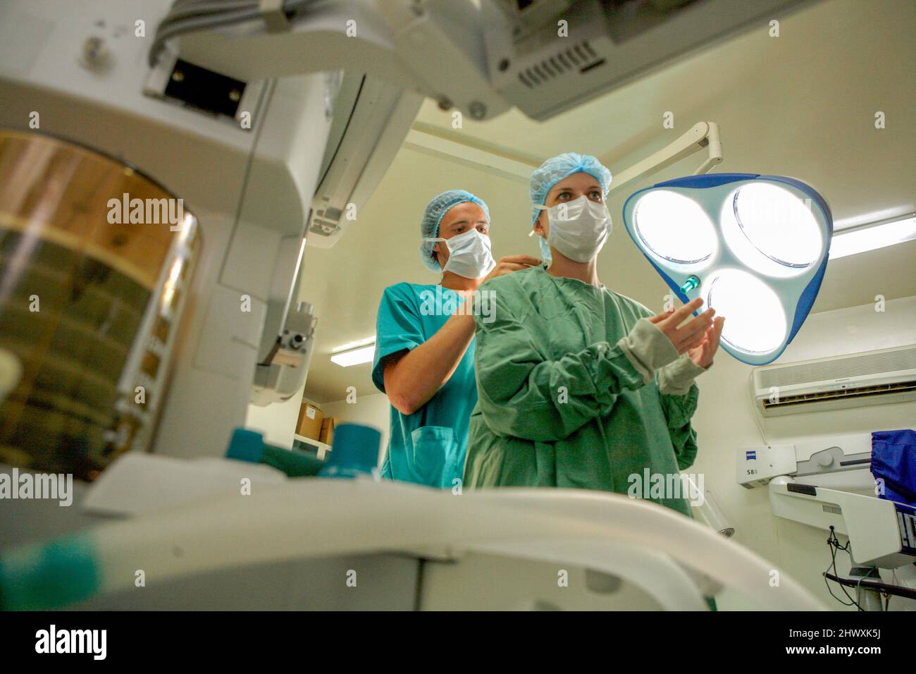 Un assistant aide le chirurgien avec ses vêtements de protection (MODÈLE RELÂCHÉ). Banque D'Images