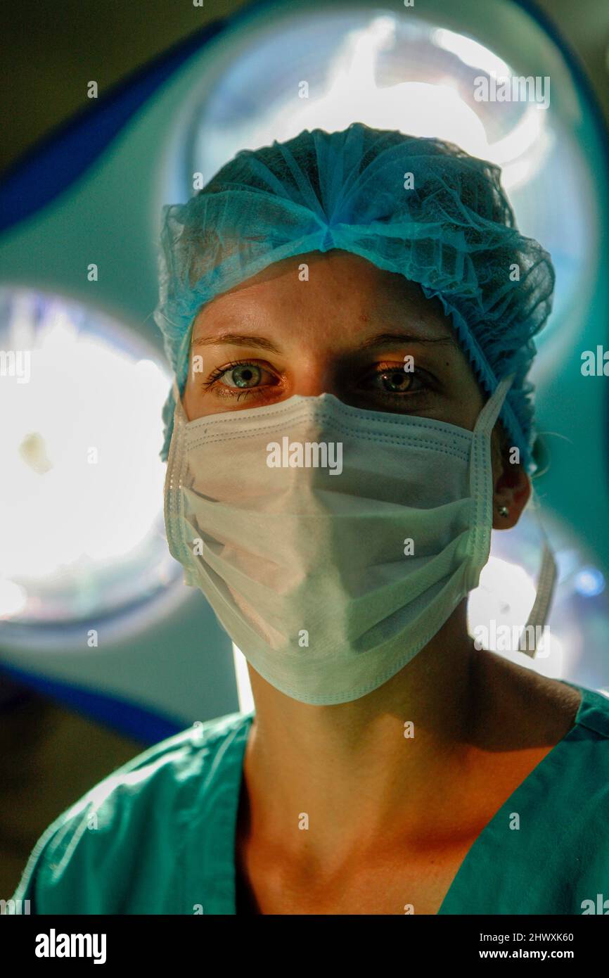 Une femme chirurgien regarde directement la caméra depuis le dessous des lampes chirurgicales (MODÈLE RELÂCHÉ) Banque D'Images