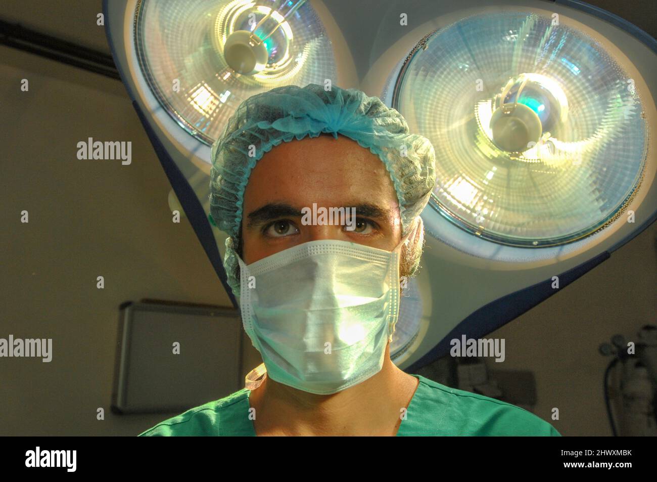 Un chirurgien masqué se tient sous un ensemble d'éclairages de la salle d'opération (MODÈLE RELÂCHÉ) Banque D'Images