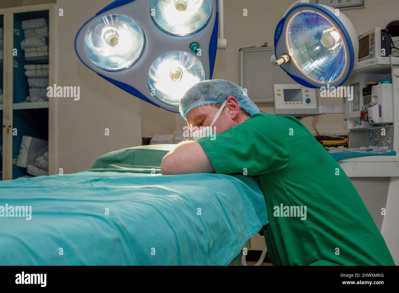 Un chirurgien fatigué et surpassé s'est posé sur une table d'opération. (MODÈLE DISPONIBLE) Banque D'Images