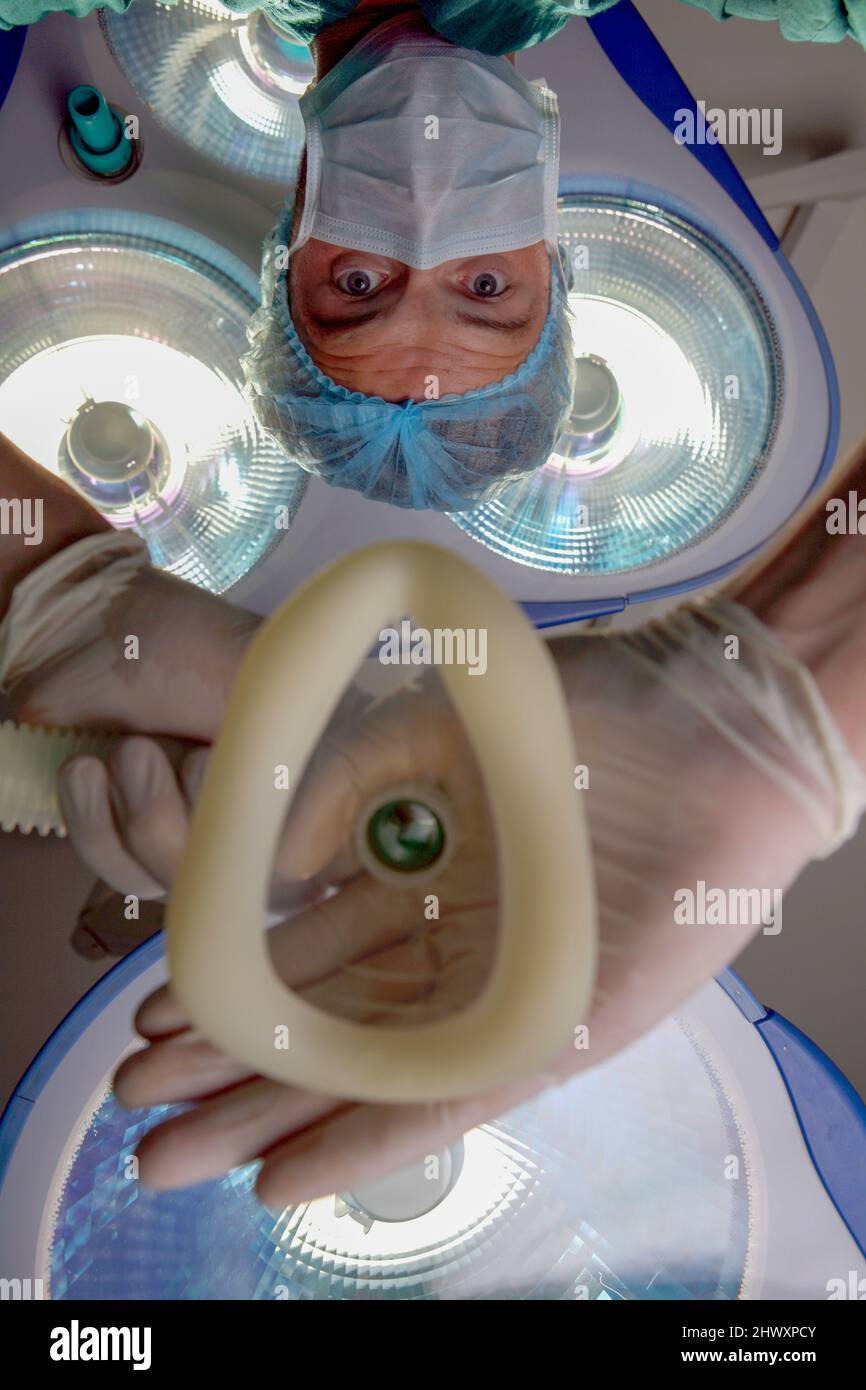 Un anesthésiste tient un masque respiratoire sous les feux de travail. Le patient souffle à travers le masque utilisé pour administrer le gaz à Banque D'Images