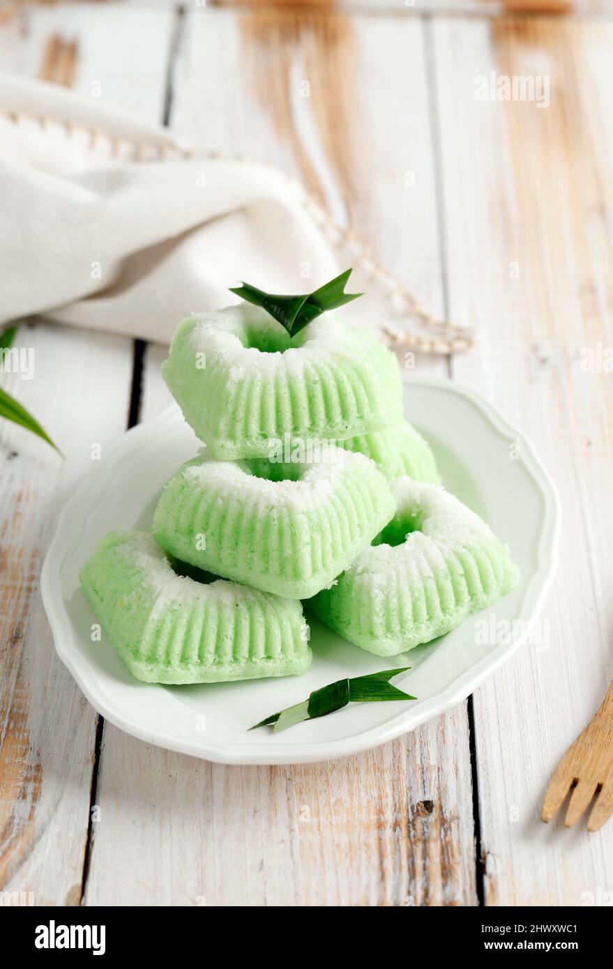 Gâteau traditionnel indonésien cuit à la vapeur Kue Putu Ayu, fait de farine de riz, de noix de coco râpée, de pandanus et de feuilles de Suji de couleur verte, servi en plat blanc Banque D'Images