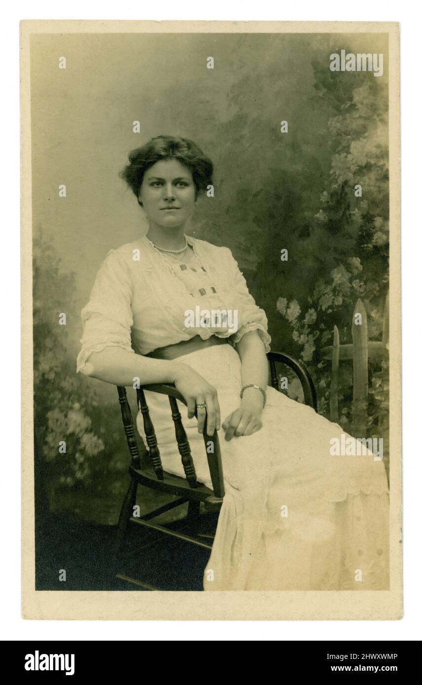 Carte postale originale d'avant WW1 ans de belle femme, fille âgée, classe moyenne ou supérieure prospère, assise, dans une robe d'été blanche, datée du 1913 juillet au verso, Royaume-Uni Banque D'Images