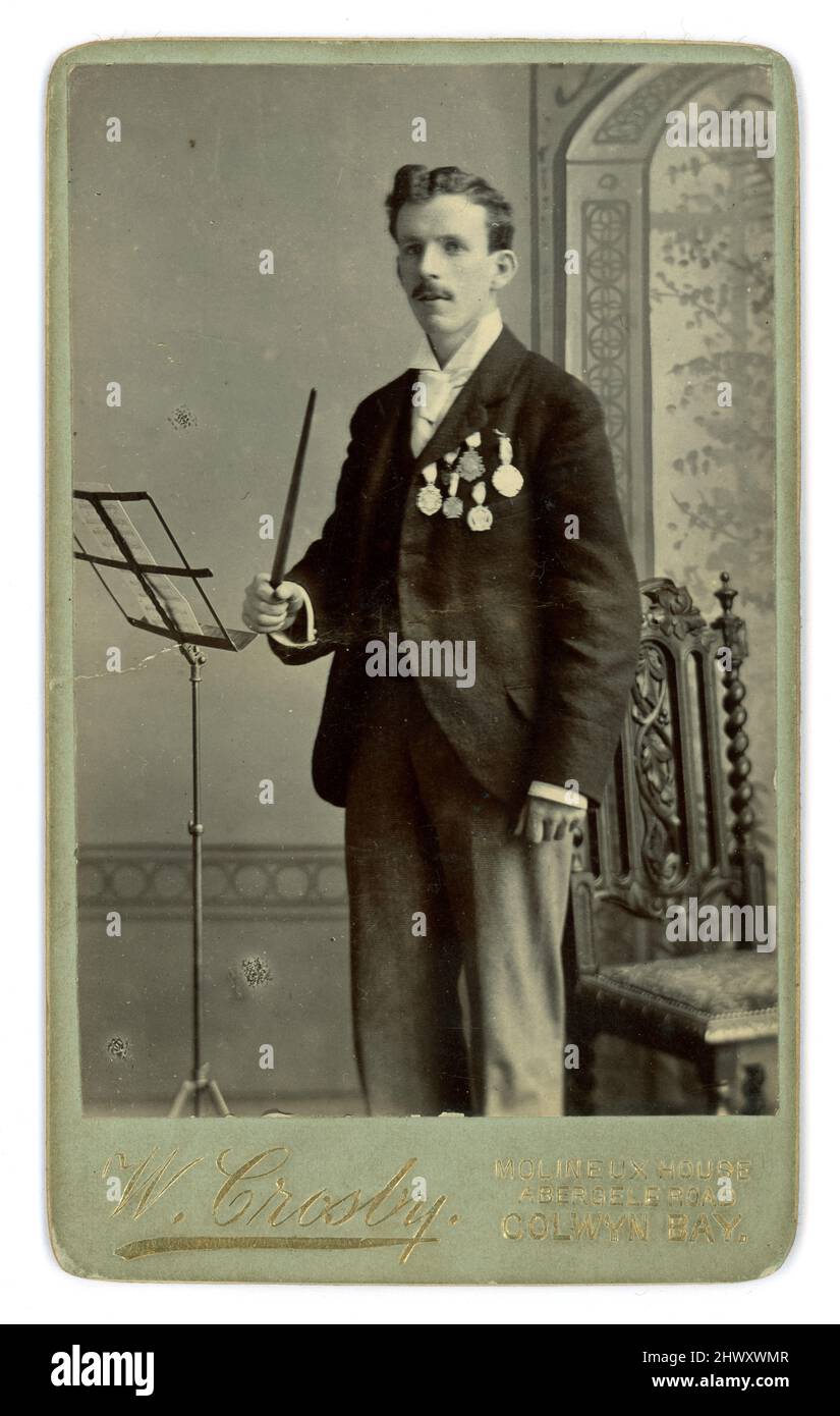 Carte de visite victorienne (CDV) ou carte de visite de jeune chef d'orchestre avec de nombreuses médailles, du studio de W. Crosby Molineux House, Abergele Road, Colwyn Bay, Anglesey, pays de Galles, Royaume-Uni vers 1890. Banque D'Images