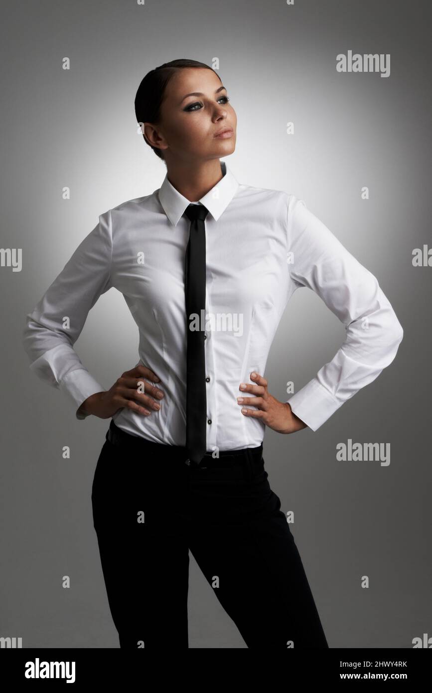 Confiant dans son style. Une jeune femme portant une chemise et une cravate  regardant latéralement avec ses mains sur les hanches Photo Stock - Alamy