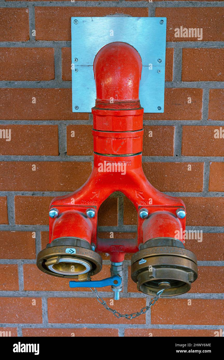 Un mur de briques rouges avec raccordement d'eau pour les pompiers. Banque D'Images