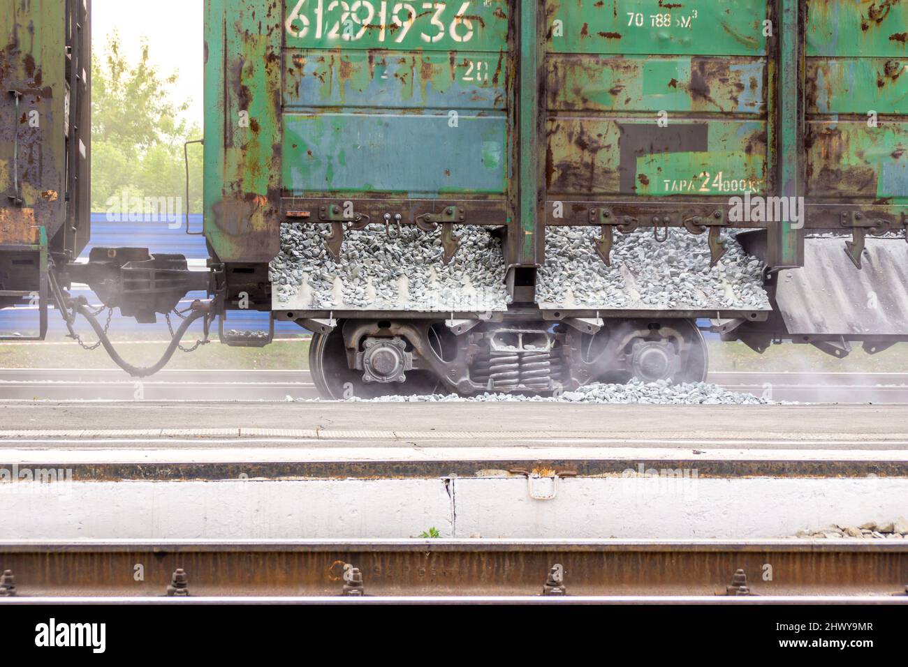 un couple de plusieurs wagons de marchandises de chemin de fer non peints conçus pour le fret en vrac sont en train de terminer le déchargement des gravats qui se trouve le long du rail, selectiv Banque D'Images