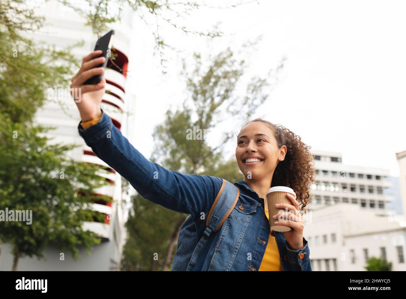 Bonne femme afro-américaine prenant selfie sur smartphone avec une tasse à café jetable Banque D'Images