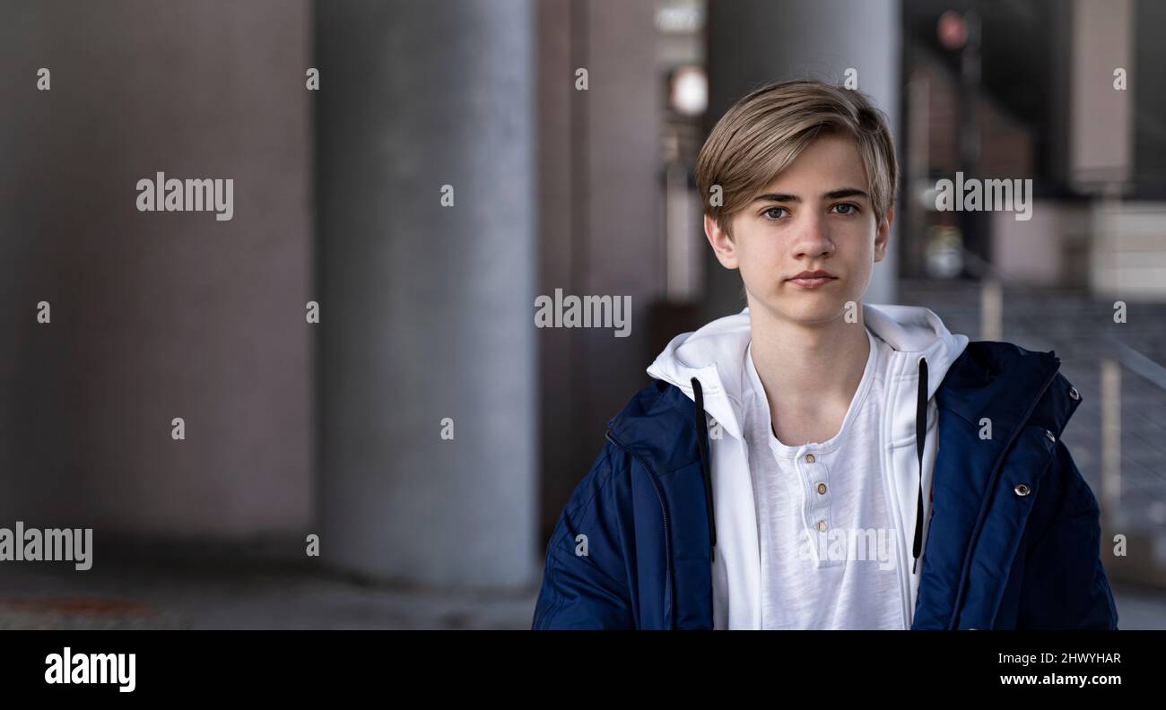Portrait d'un adolescent. Un adolescent dans une veste bleue et un t-shirt blanc regarde la caméra et sourit. Banque D'Images