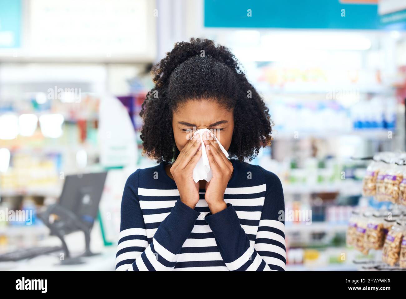 Vous avez la grippe Weve a juste le remède pour vous. Photo d'une jeune femme qui soufflait le nez dans une pharmacie. Banque D'Images