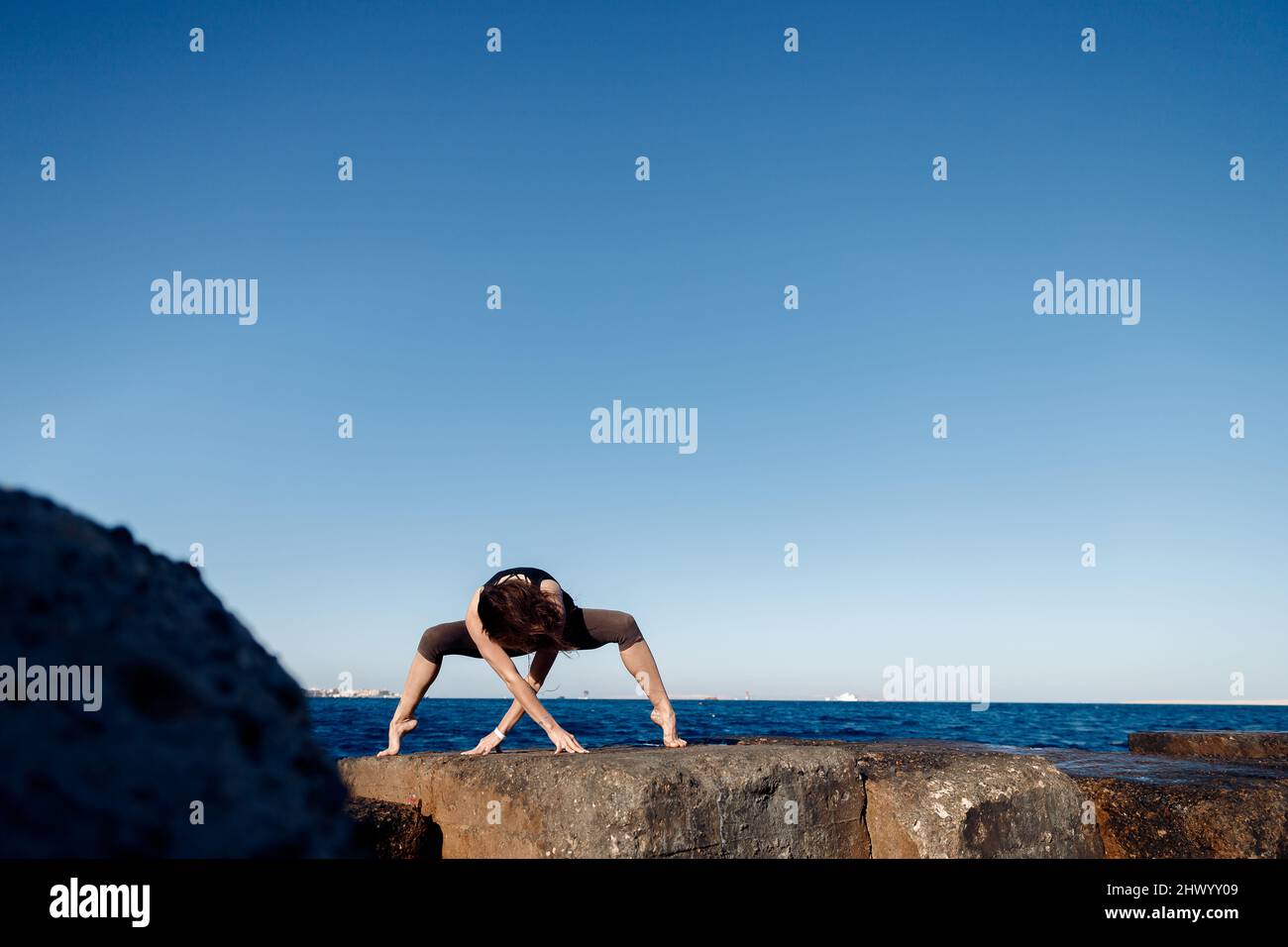 Concept femme puissance énergie vie saine. La fille pratique le yoga sur fond de mer, le vent souffle les cheveux. Banque D'Images